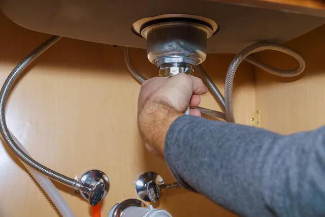 TK Plumbing technician repairing garbage disposal under kitchen sink in Sarasota